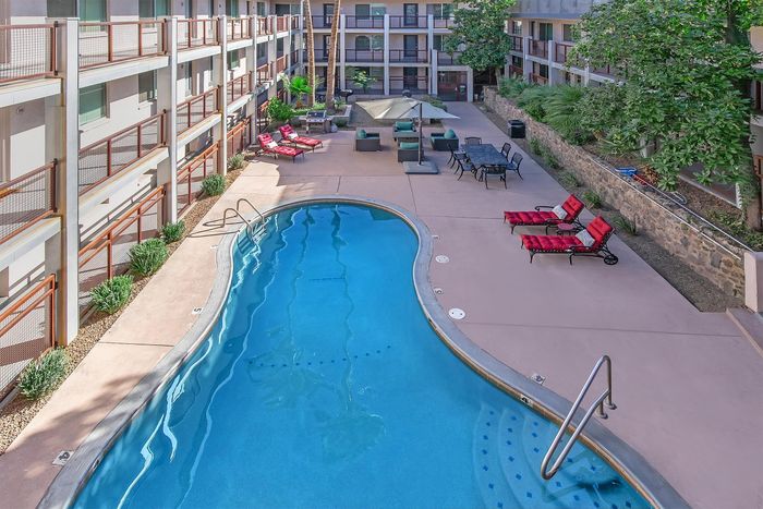 Luxurious apartment courtyard featuring a sparkling swimming pool, elegant lounge chairs, and a stylish outdoor seating area.