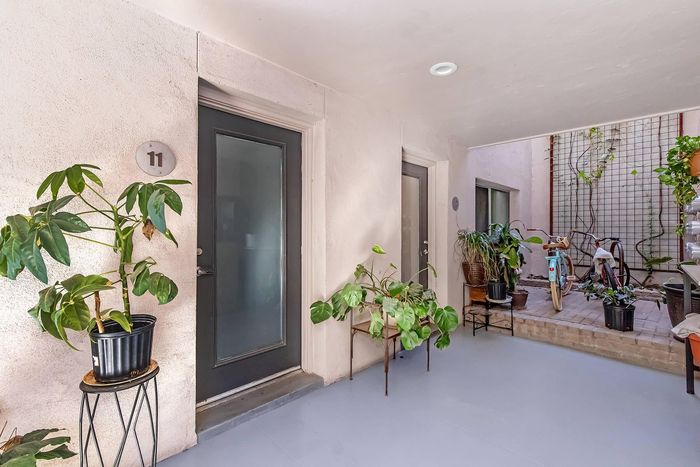 Charming apartment entrance with lush greenery and bicycles, creating a welcoming and vibrant atmosphere.