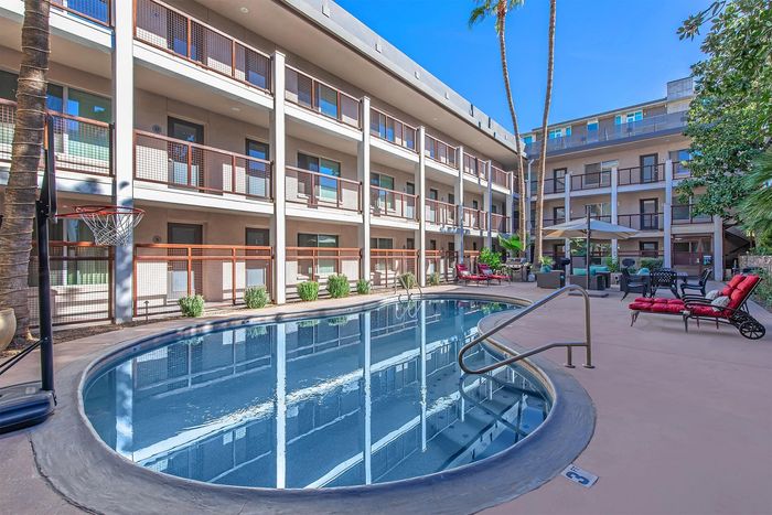 Modern apartment complex with stylish balcony views overlooking a serene round pool and elegant outdoor seating area.