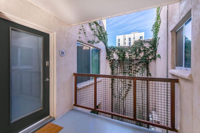 Charming apartment entrance with sleek modern door, surrounded by lush ivy and stylish railing, offering a cozy and welcoming vibe.