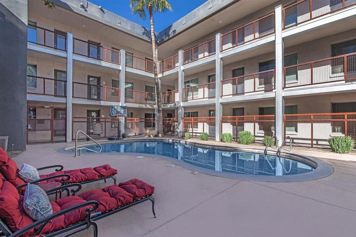 Chic apartment complex courtyard with inviting pool and stylish loungers, perfect for relaxation under the sun.