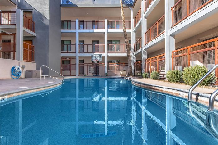 Modern apartment building with a sparkling outdoor pool, surrounded by stylish balconies and lush greenery.
