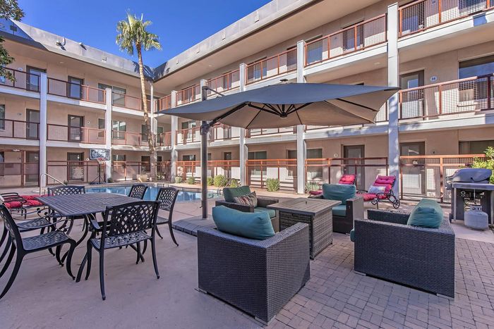 Chic apartment courtyard with inviting poolside seating, umbrella-shaded lounge, and vibrant outdoor furnishings.