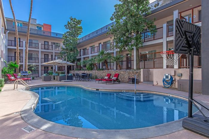 Luxurious apartment complex with a sparkling pool, stylish lounge area, and lush greenery, perfect for relaxing and entertaining.