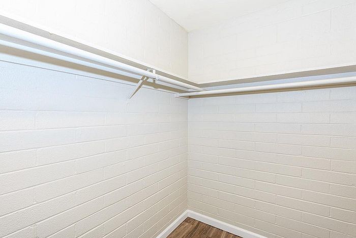 Spacious walk-in closet with clean white walls and ample hanging space, perfect for organized living.