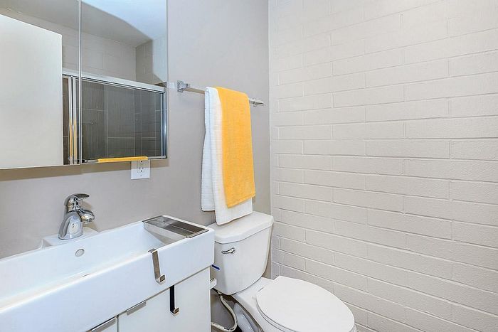 Modern bathroom with sleek design, featuring a stylish sink, mirror cabinet, and cozy tiled walls. Bright towels add a pop of color.