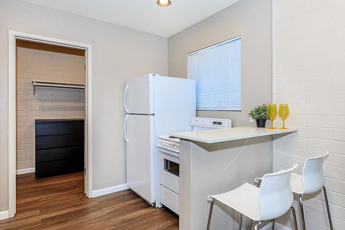 Chic kitchen nook featuring modern appliances, crisp white counters, and sleek bar seating, next to a convenient walk-in closet.
