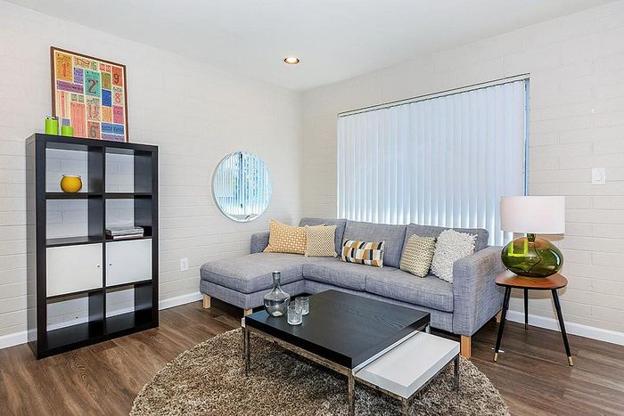 Stylish living room featuring a modern gray sectional sofa with decorative pillows, chic coffee table, and sleek shelving unit, all on elegant hardwood flooring, perfect for contemporary living.