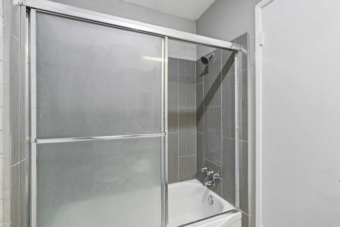 Modern bathroom with sleek glass shower doors and elegant gray tile walls.