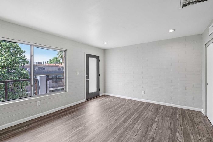 Bright and inviting living space featuring modern flooring, large window, and access to balcony with scenic views.