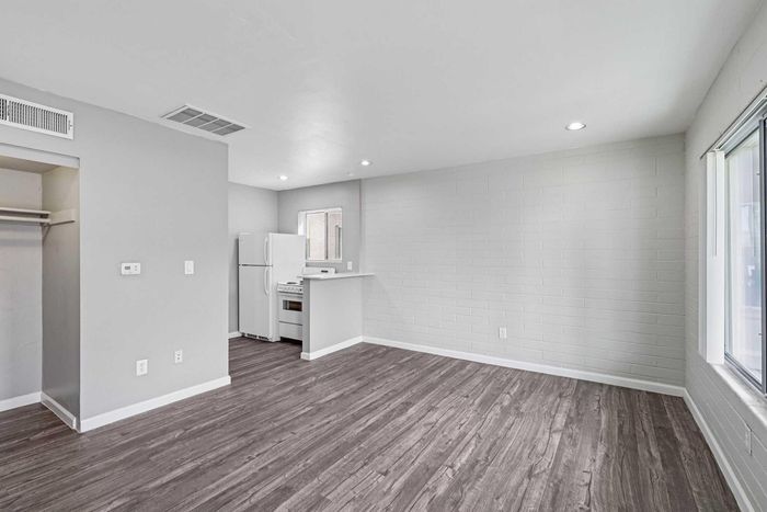 Spacious and modern apartment interior with sleek wood flooring, open living area, and bright natural light from large windows.
