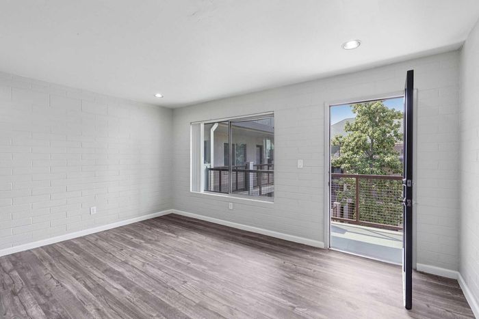 Bright and airy room with modern wooden flooring and large windows opening to a scenic balcony view.