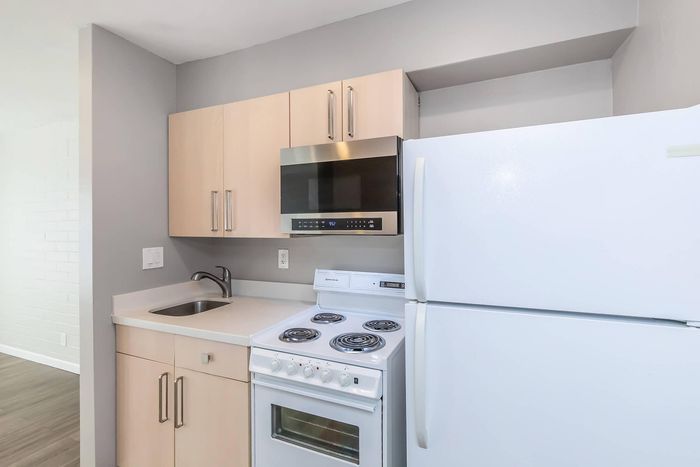 Modern kitchen with sleek cabinetry, stainless steel microwave, and spacious fridge, offering a clean and functional cooking space.