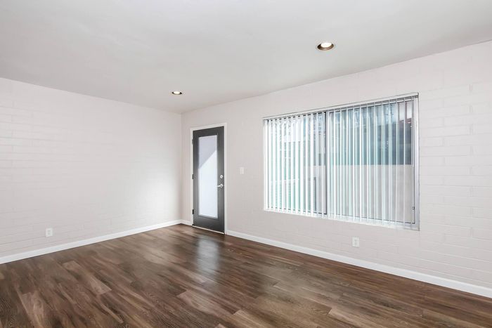 Bright and airy living room with sleek hardwood floors, modern recessed lighting, and large window offering natural light.