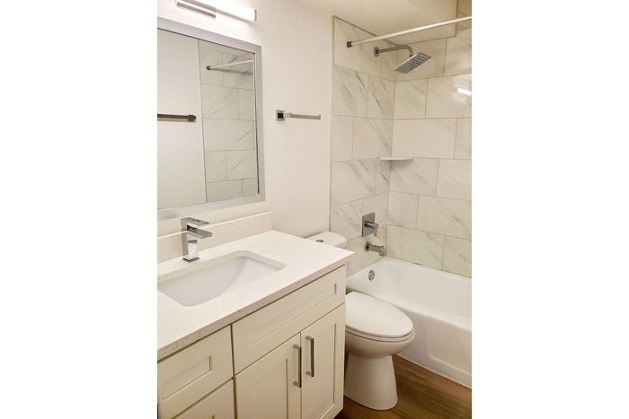 Luxurious modern bathroom with elegant marble tiles, sleek white vanity, and spacious bathtub for ultimate relaxation.