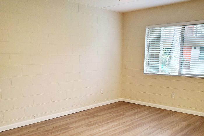 Bright and airy room with chic brick walls, elegant hardwood flooring, and a large window inviting natural light.