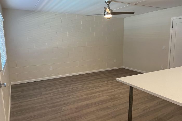 Contemporary living space with sleek laminate flooring, modern ceiling fan, and bright, neutral walls.