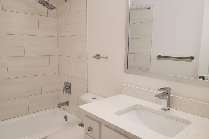 Elegant bathroom with sleek fixtures, modern vanity, and a spacious shower-tub combination in a sophisticated apartment setting.