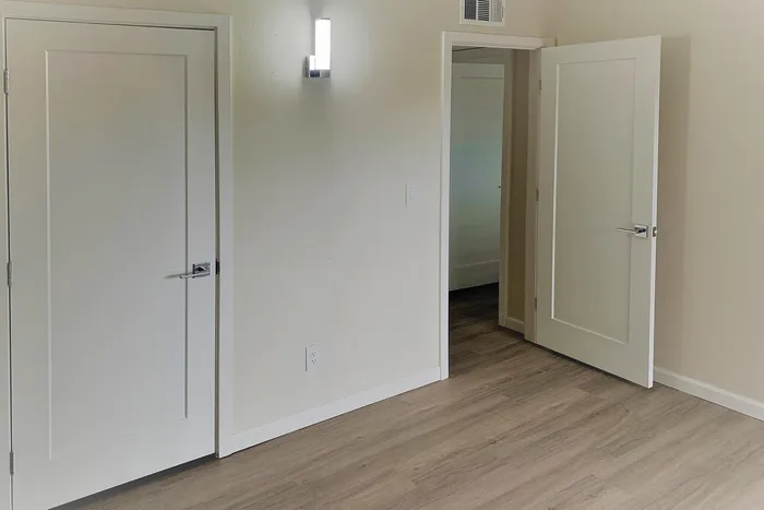 Bright and inviting apartment room with sleek wooden flooring and contemporary white doors.