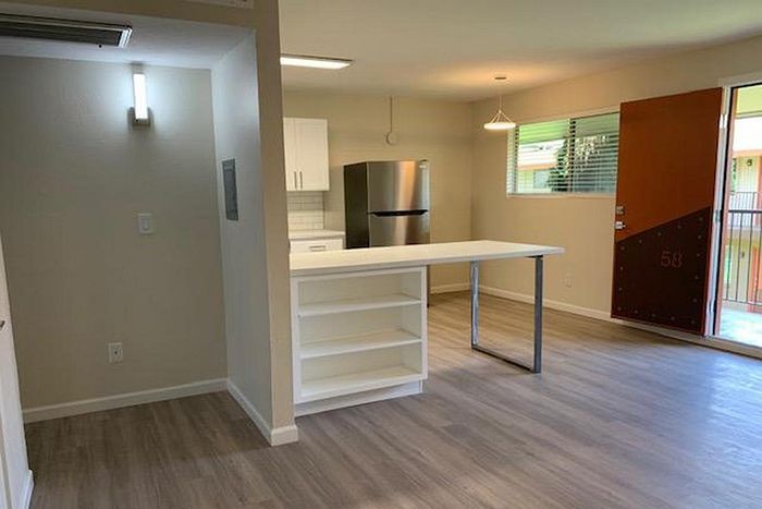 Modern open-plan kitchen with sleek stainless steel appliances, abundant natural light, and stylish wood flooring.