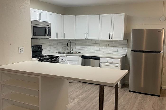 Modern kitchen with sleek white cabinetry, stainless steel appliances, and elegant subway tile backsplash.