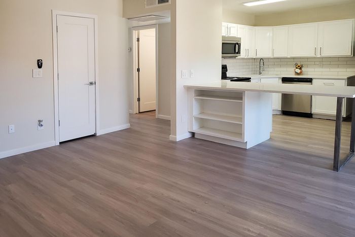 Modern open-concept kitchen with sleek white cabinetry and spacious hardwood floors in a contemporary apartment.
