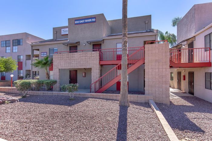 Bright and modern apartment complex with red staircases, well-maintained landscaping, and a welcoming entryway.