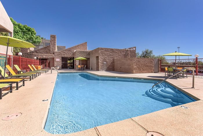Inviting outdoor pool area with vibrant lounge chairs and shaded tables, set against a stunning modern architectural backdrop.