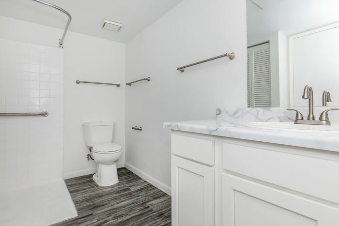 Bright and modern bathroom featuring elegant marble countertops, stainless steel fixtures, and spacious shower area.