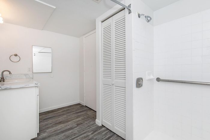 Sleek modern bathroom with elegant wood flooring, stylish marble countertop, and a spacious shower area.