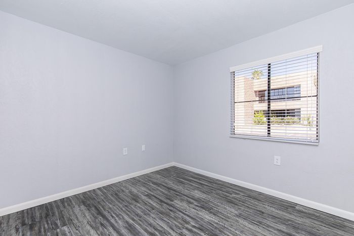 Bright and airy room featuring sleek hardwood floors and a large window with a picturesque view, perfect for creating a cozy living space.