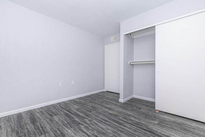 Modern empty bedroom with sleek gray flooring and built-in closet space, offering a clean and open design.