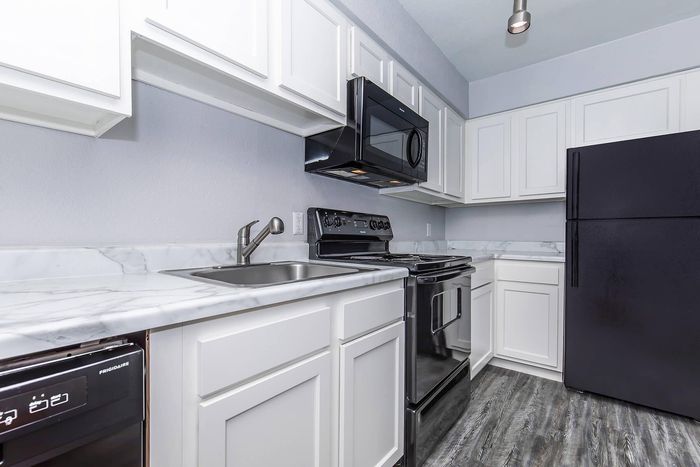 Modern kitchen with sleek black appliances, elegant white cabinets, and chic marble countertops.