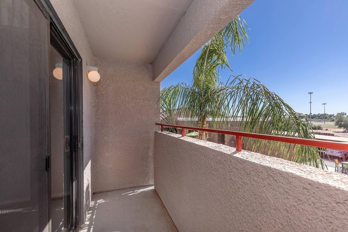 Inviting balcony view with palm trees and bright blue sky, perfect for outdoor relaxation.