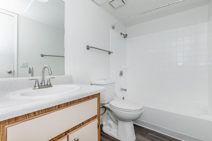 Modern bathroom showcasing sleek white countertops, polished fixtures, and a pristine bathtub with elegant tile accents.