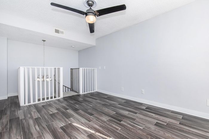 Bright modern room with elegant wood-style flooring and a sleek ceiling fan, perfect for a cozy retreat.