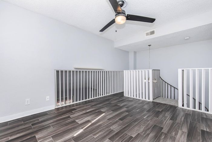 Bright and airy loft space with modern wood-look flooring and sleek ceiling fan, offering a stylish and inviting ambiance.