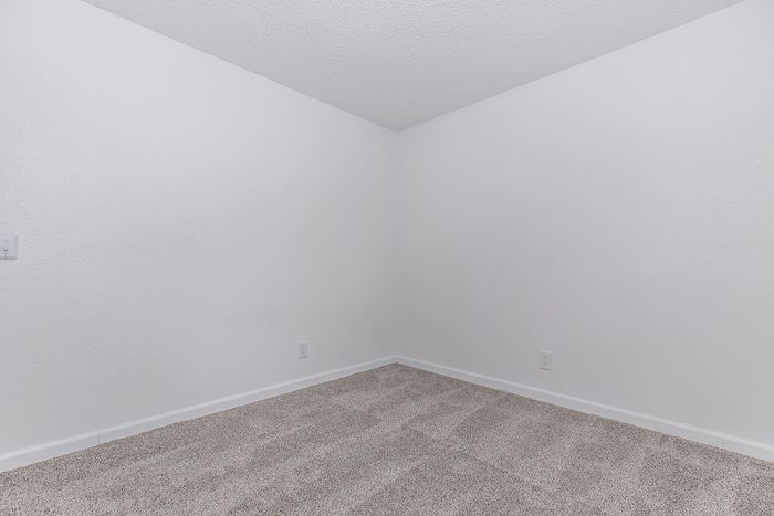 Bright bedroom with plush carpeting and crisp white walls, perfect for personalizing your living space.