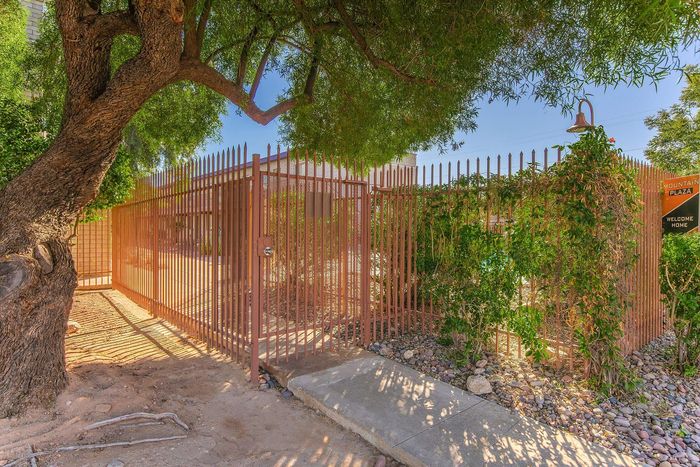 Charming entrance to Mountain Plaza with a welcoming gated pathway and lush greenery under the shade of a mature tree.