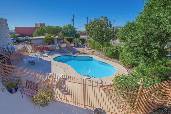 Charming outdoor pool area with sun loungers and lush greenery, perfect for relaxation in a serene environment.