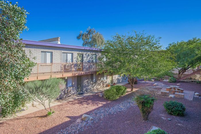 Charming apartment exterior with lush greenery, stone pathways, and inviting outdoor seating areas.