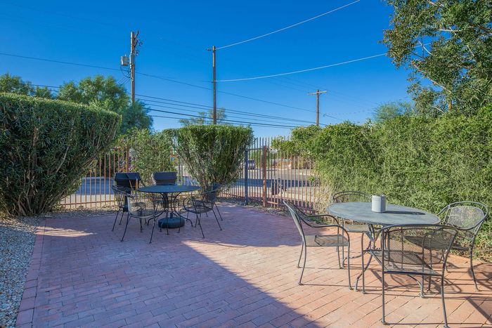 Charming outdoor patio with elegant metal furniture, surrounded by lush greenery and offering a serene social space.