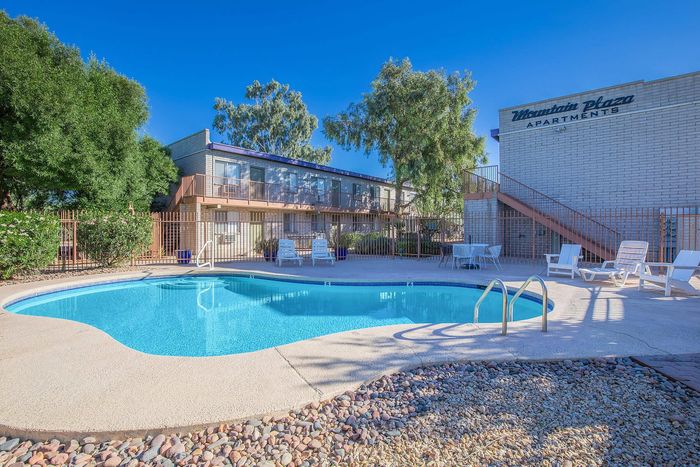 Inviting outdoor swimming pool area at Mountain Plaza Apartments surrounded by lush greenery and modern architecture, perfect for relaxation.