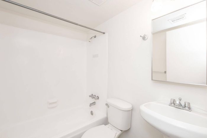 Pristine bathroom featuring a sleek white tub, modern fixtures, and a large mirror for a spacious feel.