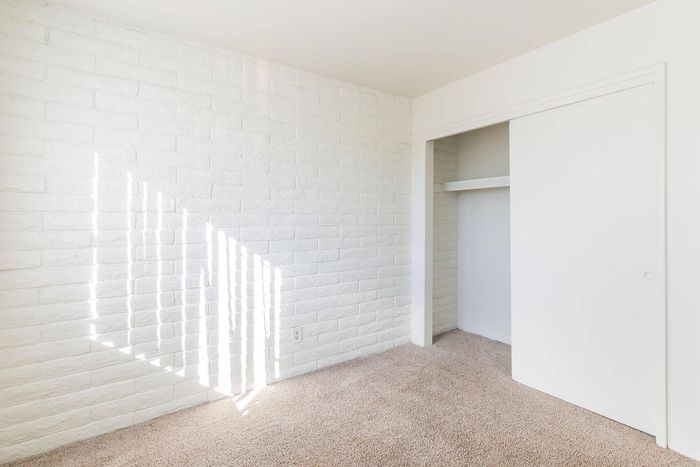 Bright room with fresh white brick walls, cozy carpet, and a spacious built-in closet.