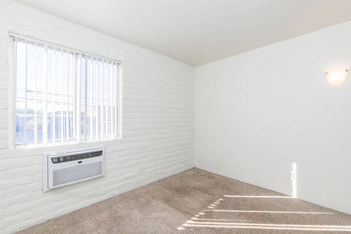 Bright and airy room with large windows, featuring fresh white walls and cozy carpet flooring, ideal for a comfortable living space.