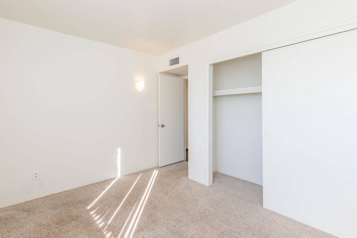 Bright room with plush carpet, a built-in closet, and soft ambient lighting, perfect for a cozy retreat.