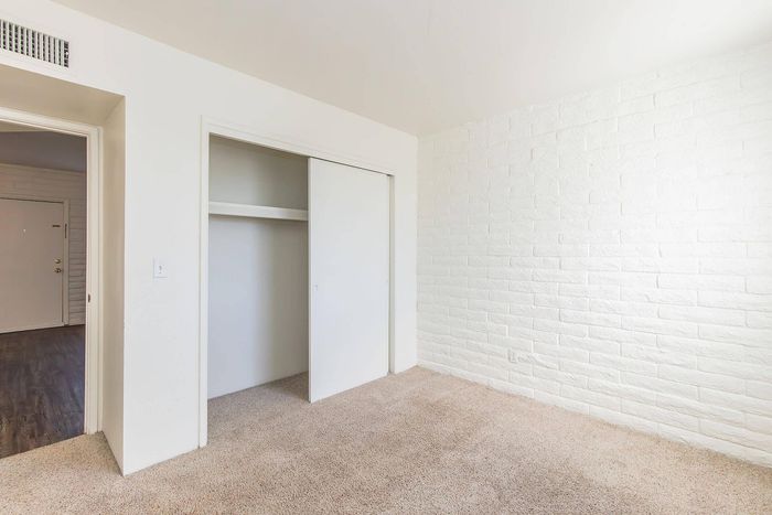 Bright and airy bedroom with plush carpeting, spacious closet, and elegant white brick accent wall.