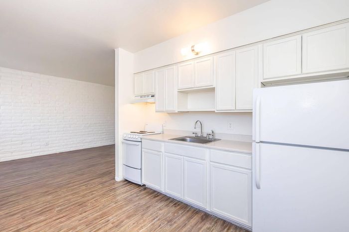 Bright and airy kitchen with sleek white cabinetry and modern appliances, featuring elegant wood flooring and a cozy open layout.