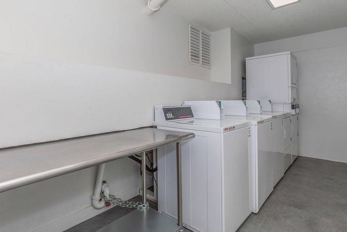 Modern laundry room equipped with multiple washing and drying machines, featuring a convenient folding table in a spacious and bright setting.